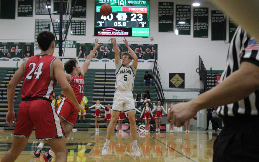 boy shooting basketball and another boy blocking and one watching