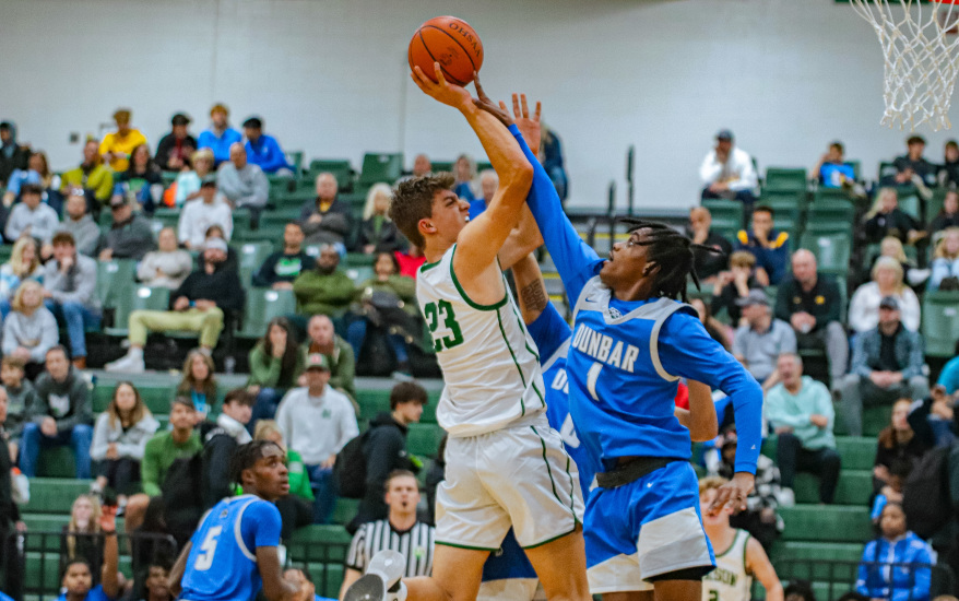 boy shooting basketball and another boy blocking