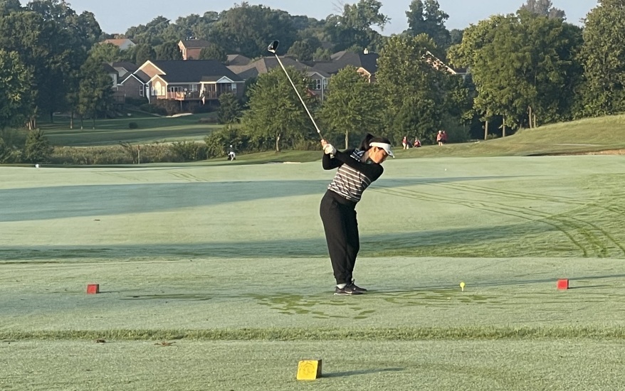 girl hitting golf ball with club